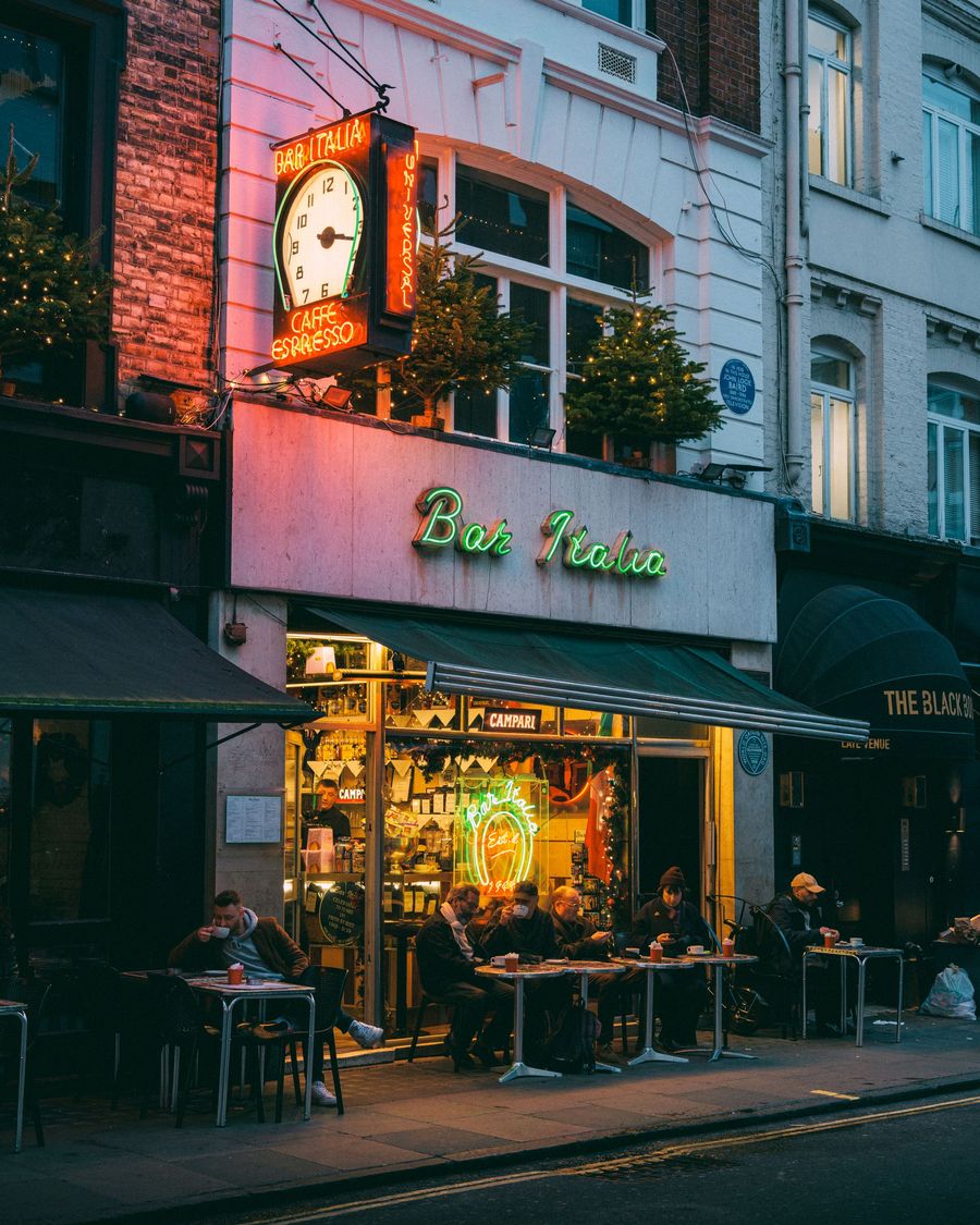 The neon sign and clock above Bar Italia on Frith Street in London at dusk