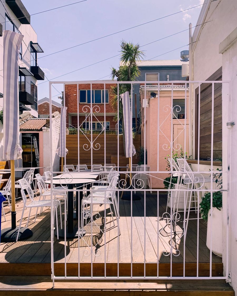 An empty café courtyard with white chairs behind an iron gate in Melbourne