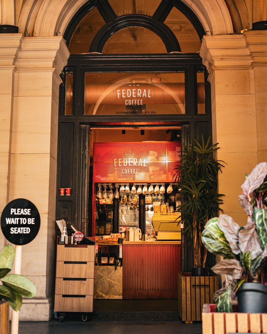 A warmly lit café counter seen through a stone archway in Melbourne