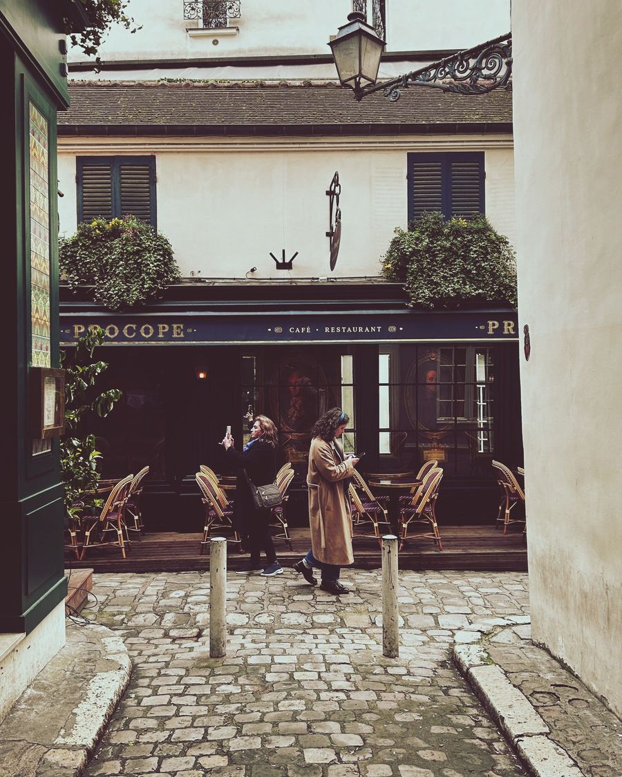 The green shopfront of Le Procope on a cobbled lane in Paris