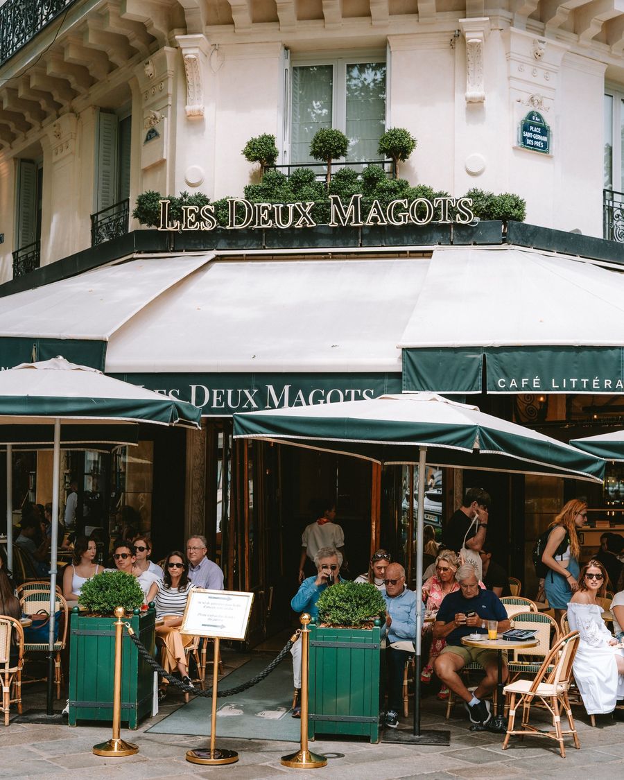 Customers at the green-awninged terrace of Les Deux Magots in Paris