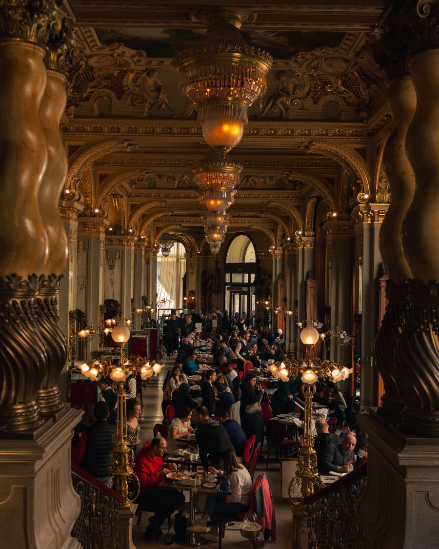 The gilded, chandeliered dining room of the New York Café in Budapest, full of guests