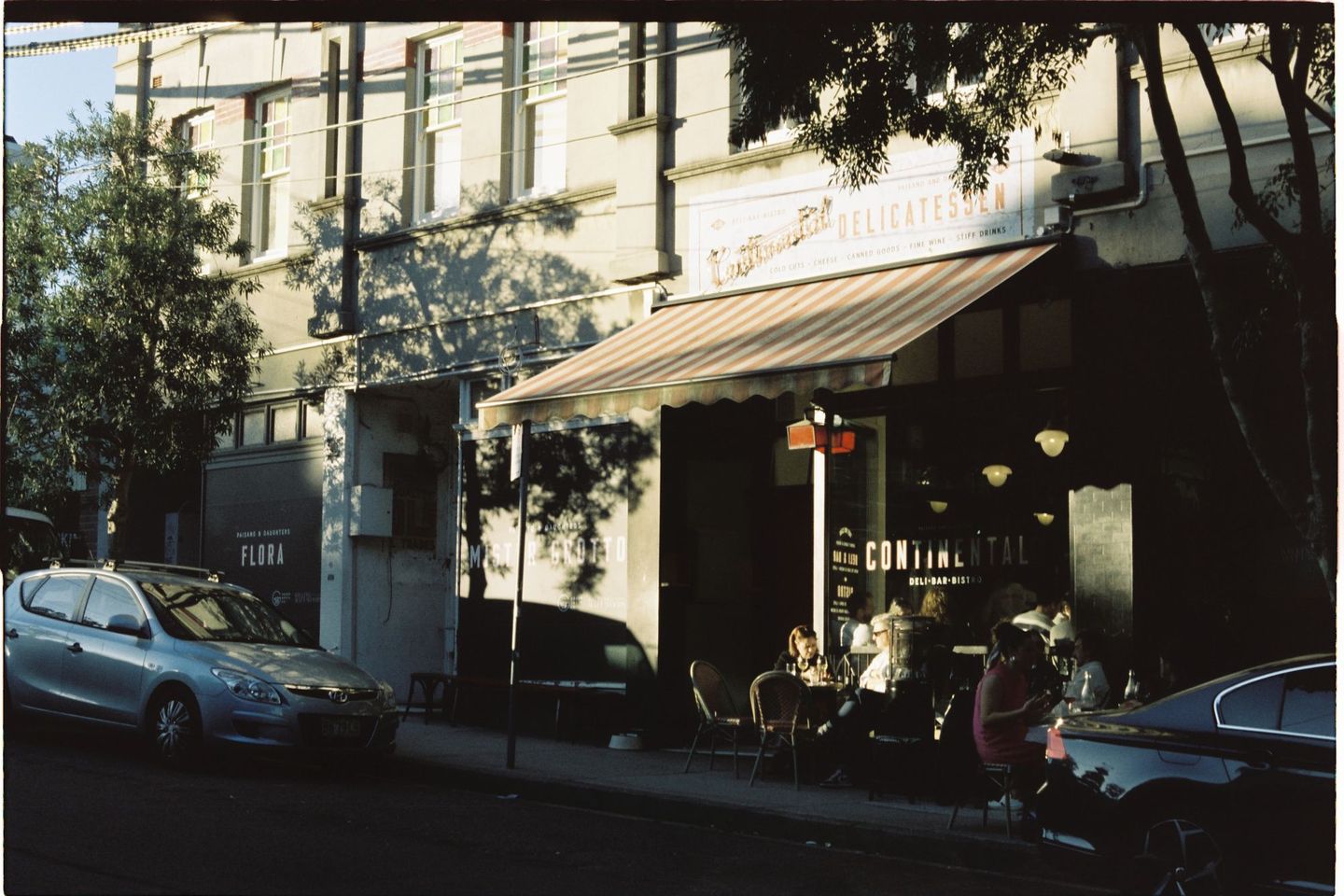 A café awning on a leafy street in Newtown, Sydney, in late afternoon light