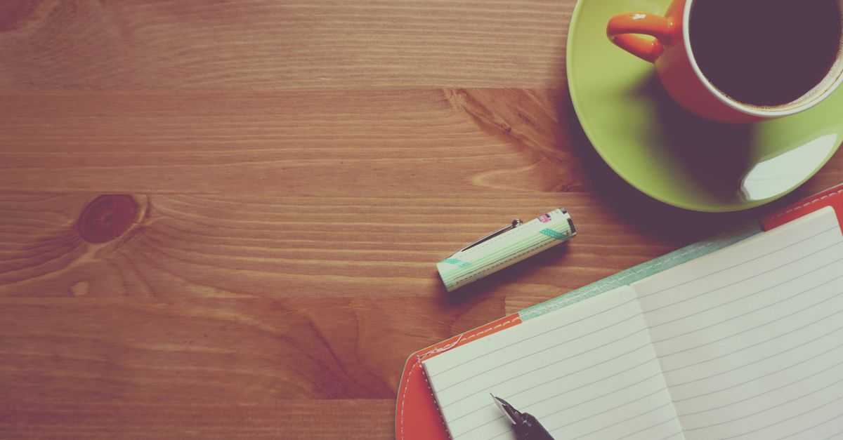 A coffee cup beside an open notebook on a café table, set up for a mentoring conversation
