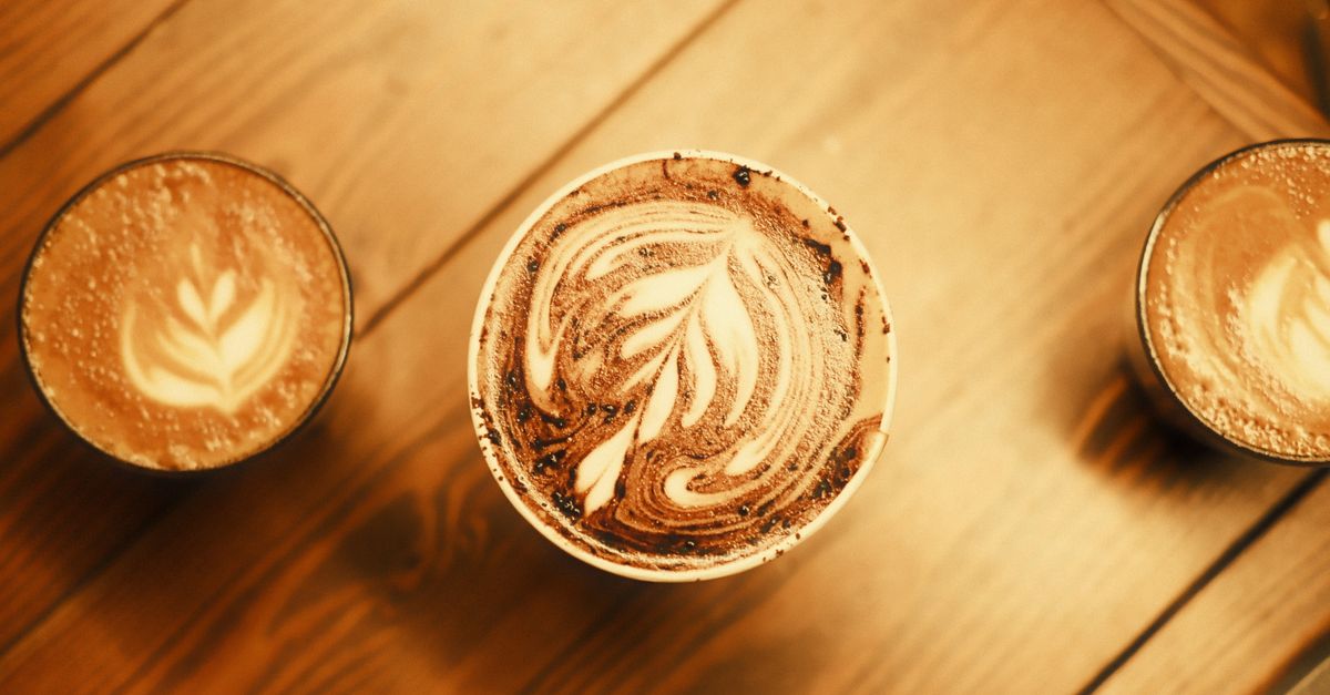 Two coffee cups facing each other across a small café table, set for a first conversation
